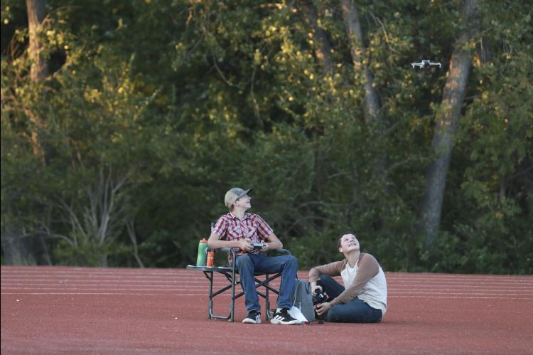 Darren Kempke, left, and Brian McClendon watch the drone lift off the track near the end zone at Shanelec Field during the Sept. 4 football game.