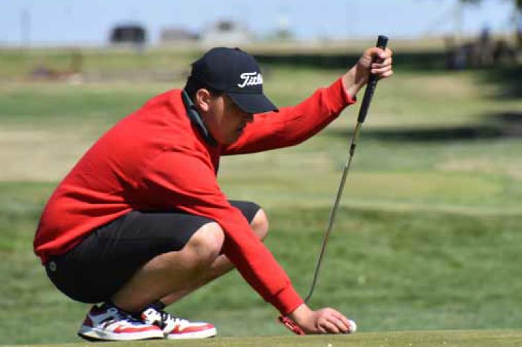 Senior Aidan Johnson lines up his ball for a putt on the Minneapolis Golf Course. Photos by CATHERINE DOUD/Ellsworth County Independent-Reporter