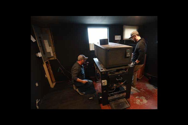 Workers prepare to remove the old projector on the podium at the Kanopolis Drive-In March 2 to make room for a 4K laser projector. KAREN BONAR/Ellsworth County Independent-Reporter