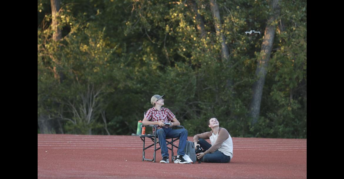 Darren Kempke, left, and Brian McClendon watch the drone lift off the track near the end zone at Shanelec Field during the Sept. 4 football game.
