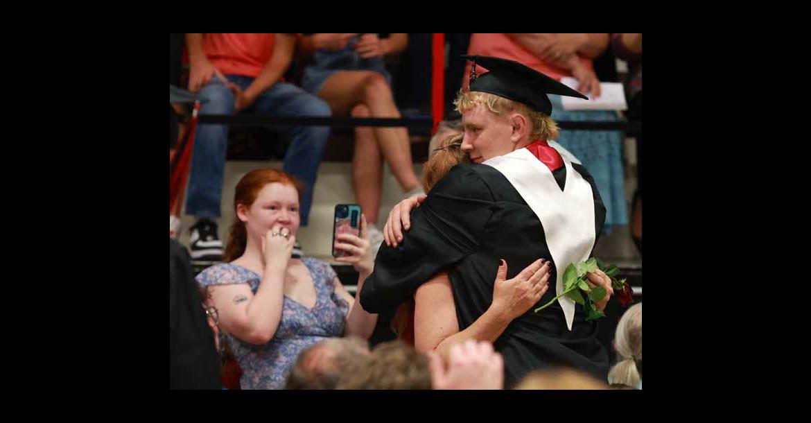 Micah Galvan hugs his mom, Heather McClendon, as Ambriana McClendon captures the moment on her phone. Seniors handed a rose to a significant adult near the start of commencement. Photos by KAREN BONAR/Ellsworth County Independent-Reporter