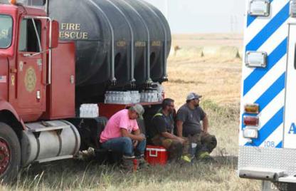 Members of the Ellsworth Rural Fire Department cool off in the shade of a truck during a recent fire. KAREN BONAR/Ellsworth County Independent-Reporter