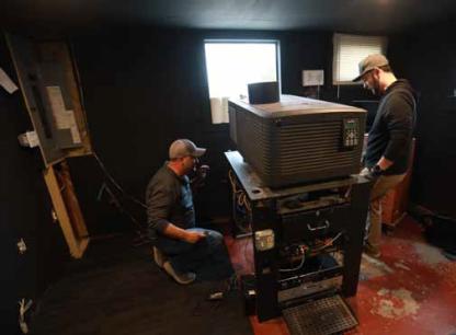 Workers prepare to remove the old projector on the podium at the Kanopolis Drive-In March 2 to make room for a 4K laser projector. KAREN BONAR/Ellsworth County Independent-Reporter