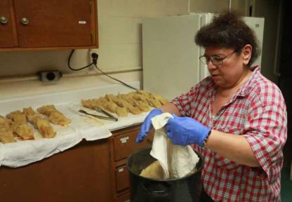 Phyllis Orozco unwraps tamales for take-out orders in advance of the annual fiesta at St. Ignatius of Loyola Church.